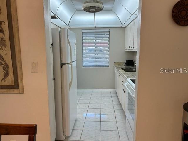 kitchen with white cabinets, light tile patterned floors, and white appliances