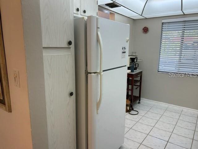 kitchen with light tile patterned floors and white fridge