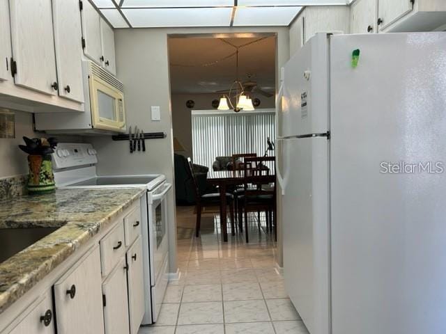 kitchen with white cabinetry, light stone countertops, white appliances, and an inviting chandelier