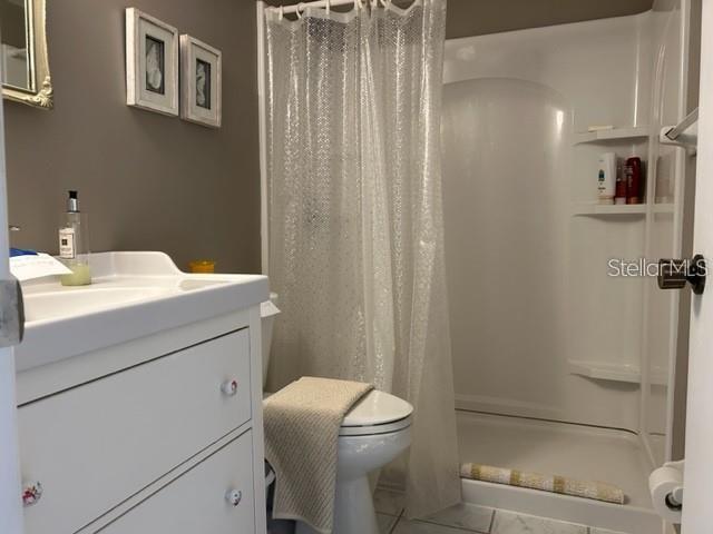 bathroom featuring a shower with curtain, tile patterned flooring, vanity, and toilet