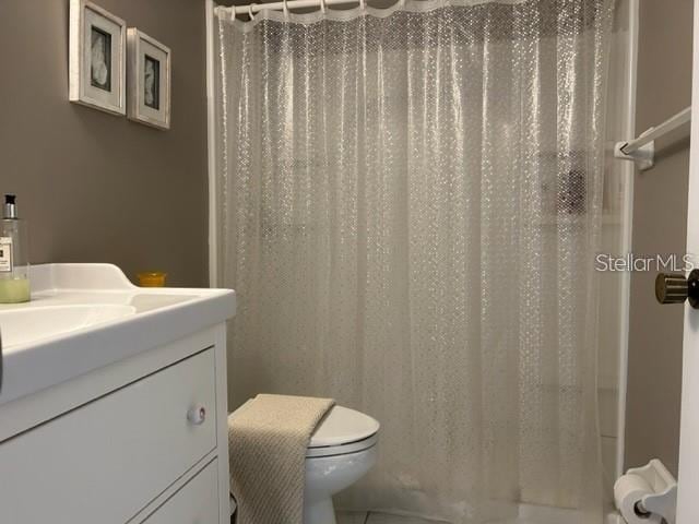 bathroom featuring vanity, curtained shower, and toilet