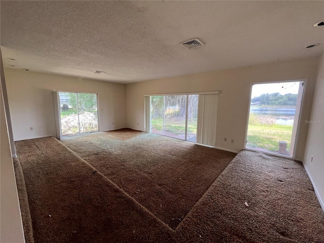 carpeted empty room featuring a textured ceiling