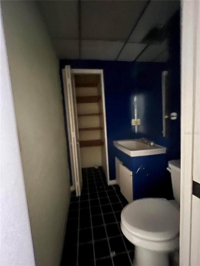 bathroom featuring tile patterned floors, a paneled ceiling, vanity, and toilet