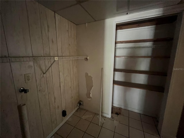 washroom featuring wooden walls and light tile patterned flooring