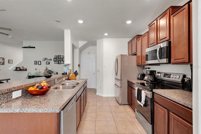 kitchen featuring sink, light tile patterned floors, stainless steel appliances, and a textured ceiling