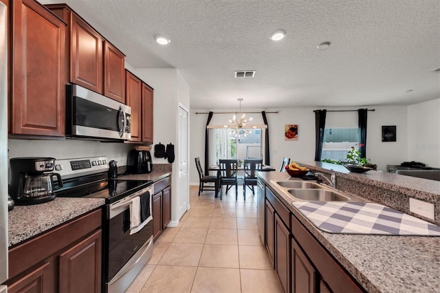 kitchen with an inviting chandelier, sink, hanging light fixtures, light tile patterned flooring, and stainless steel appliances