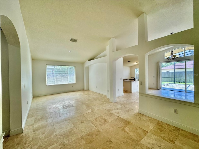 interior space featuring a wealth of natural light, a textured ceiling, a chandelier, and lofted ceiling