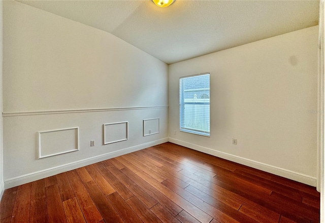 spare room with a textured ceiling, vaulted ceiling, and dark hardwood / wood-style flooring