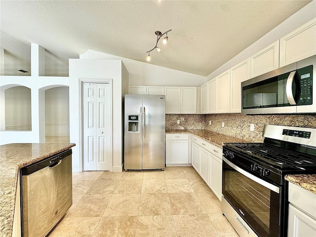 kitchen with a textured ceiling, appliances with stainless steel finishes, white cabinetry, lofted ceiling, and stone counters