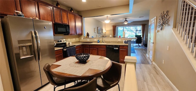 kitchen featuring decorative light fixtures, black appliances, sink, ceiling fan, and kitchen peninsula