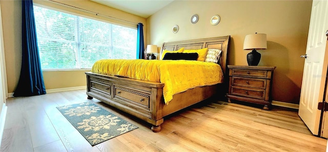 bedroom with vaulted ceiling and light wood-type flooring