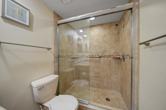 bathroom featuring toilet and a shower with shower door