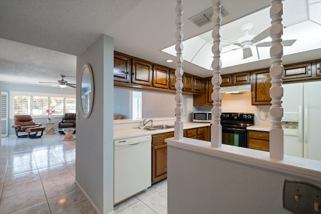 kitchen with a textured ceiling, sink, light tile patterned flooring, and white appliances