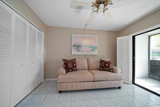 tiled living room with ceiling fan and a textured ceiling