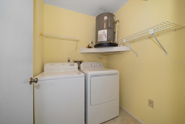 clothes washing area with a textured ceiling, electric water heater, and washing machine and clothes dryer