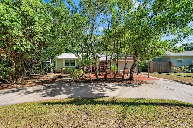 ranch-style home with a front lawn and a patio area