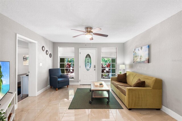 living room featuring ceiling fan and a textured ceiling