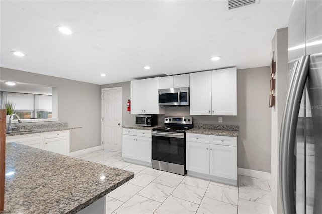 kitchen with sink, white cabinets, stone countertops, and appliances with stainless steel finishes