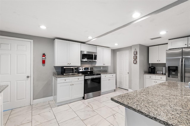 kitchen featuring white cabinets, stainless steel appliances, and light stone counters