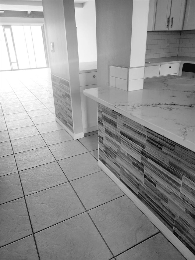 kitchen with tile walls, light stone counters, backsplash, and light tile floors