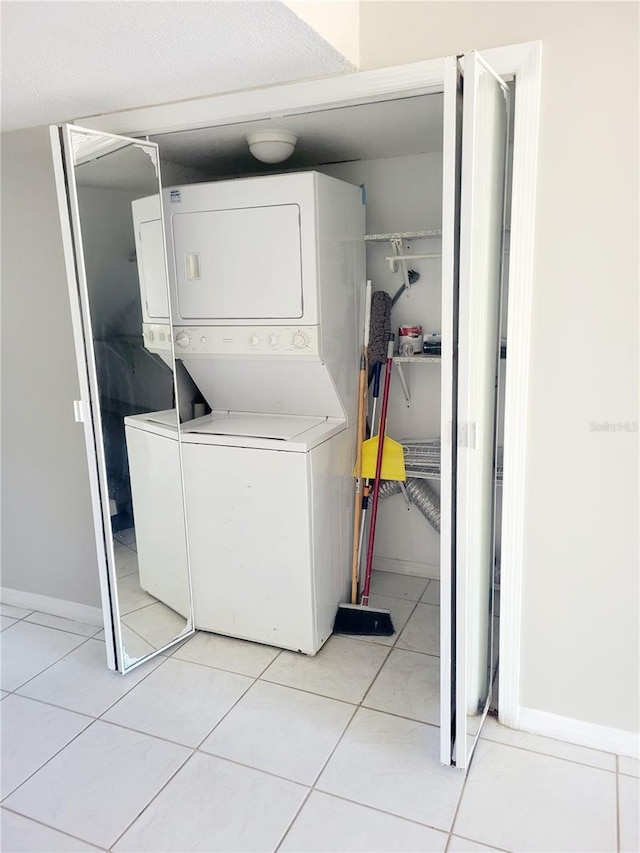 laundry room featuring stacked washer and dryer and light tile floors