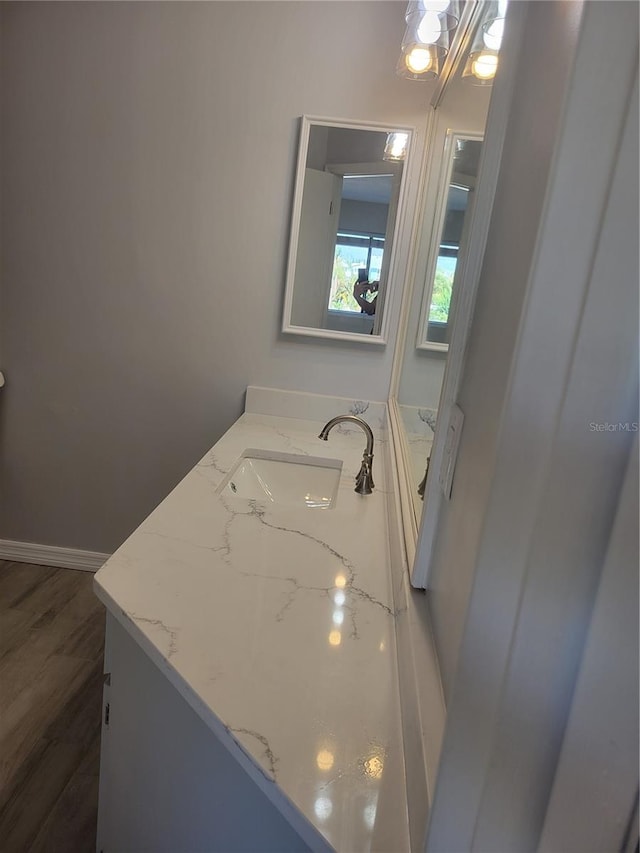 bathroom featuring wood-type flooring and vanity with extensive cabinet space