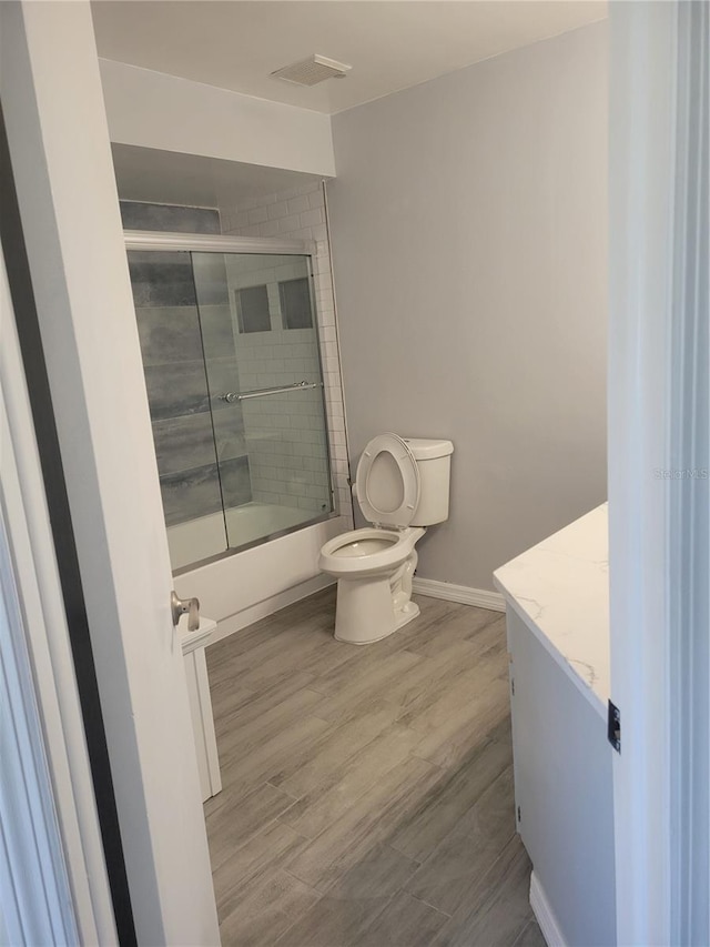 318 Windrush Blvd Unit 9, Indian Rocks Beach, FL 33785 - bathroom with toilet, vanity, enclosed tub / shower combo, wood finished floors, and baseboards