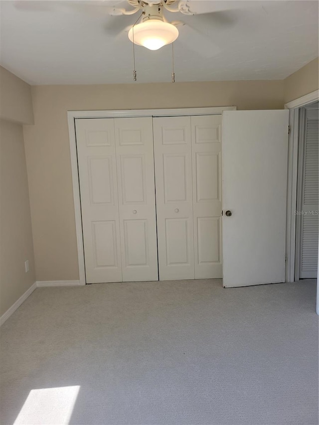 unfurnished bedroom featuring light carpet, a closet, and ceiling fan