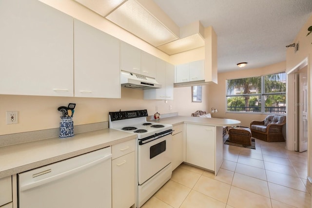 kitchen with light tile patterned flooring, white appliances, kitchen peninsula, and white cabinets