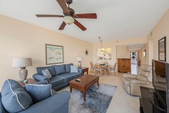 living room featuring light tile patterned flooring, ceiling fan, and a textured ceiling