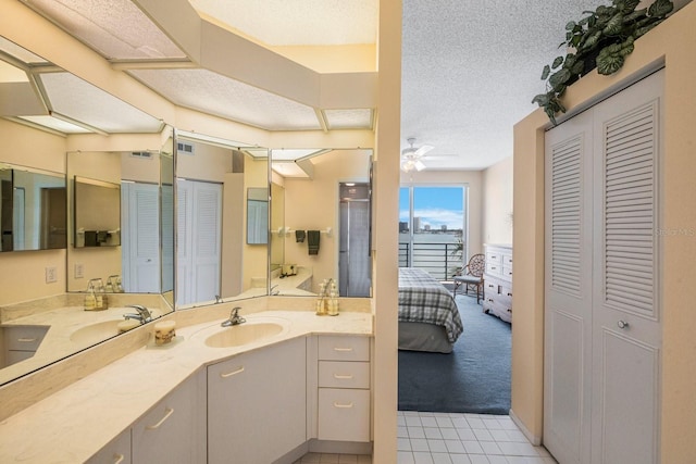 bathroom with tile patterned floors, ceiling fan, vanity, and a textured ceiling