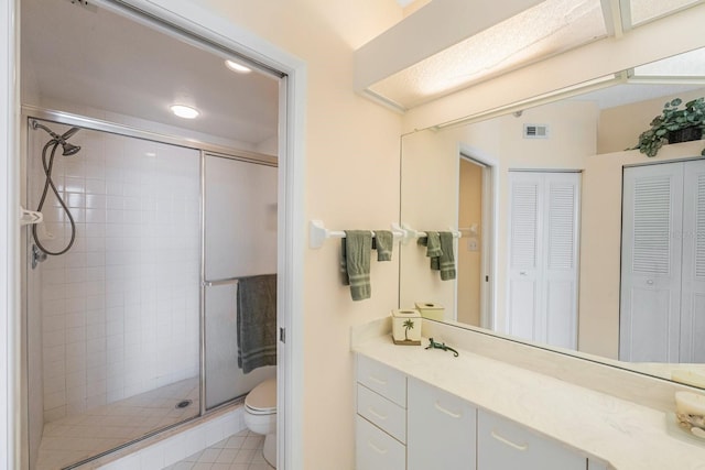 bathroom featuring tile patterned flooring, walk in shower, vanity, and toilet