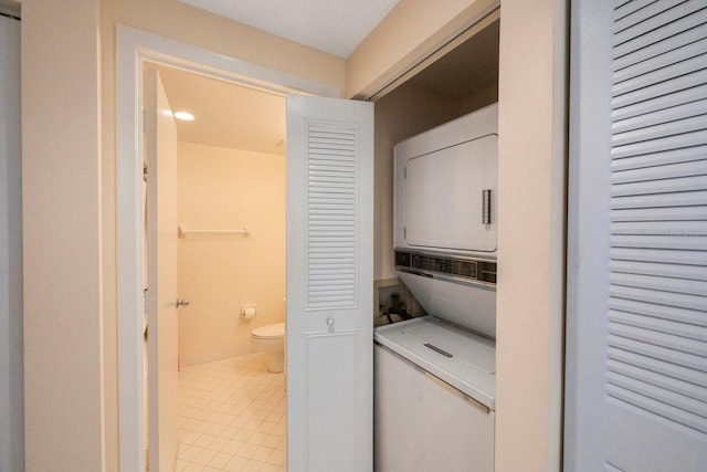 laundry area with stacked washer / dryer and tile patterned flooring