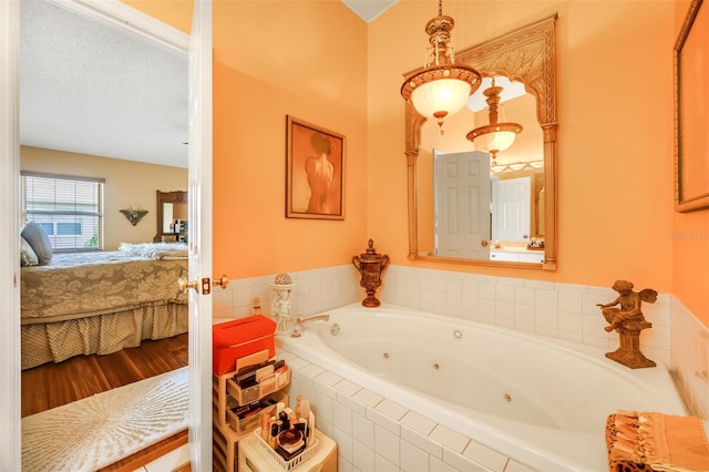 ensuite bathroom featuring wood finished floors, a jetted tub, a textured ceiling, and ensuite bathroom