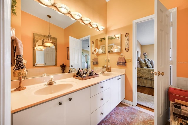 full bath with ensuite bathroom, double vanity, a sink, and tile patterned floors