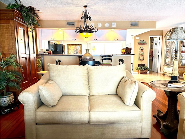 living area with a textured ceiling, wood finished floors, and visible vents