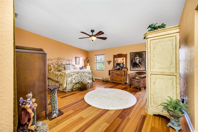 bedroom featuring ceiling fan, wood finished floors, and baseboards