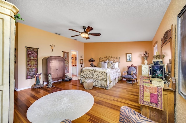 bedroom featuring visible vents, a ceiling fan, a textured ceiling, wood finished floors, and baseboards