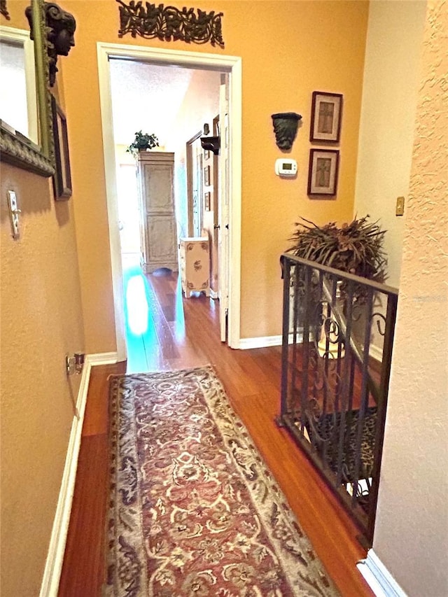 hall with baseboards and wood finished floors