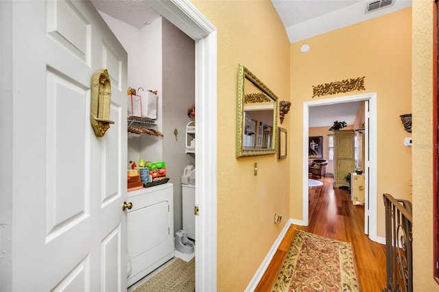 hallway featuring washer / dryer, light wood-style flooring, visible vents, and baseboards