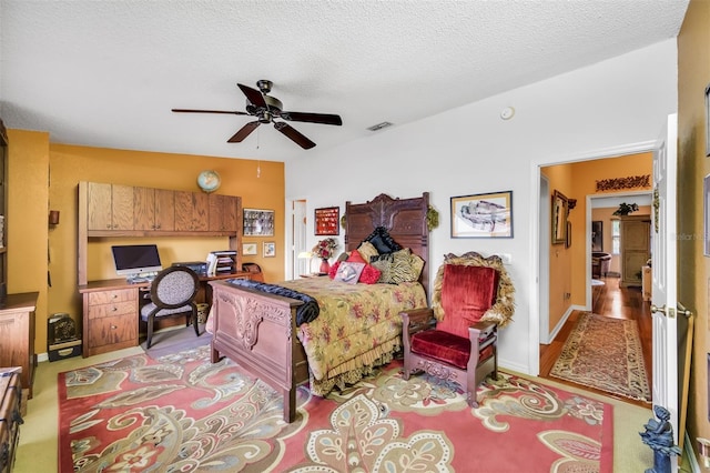 bedroom featuring a ceiling fan, visible vents, a textured ceiling, and baseboards