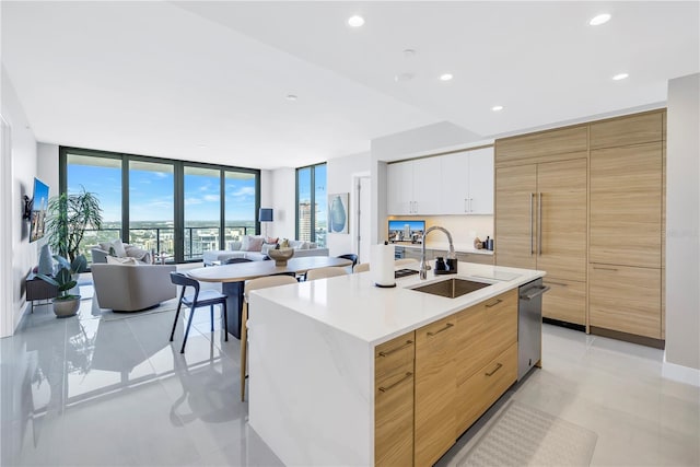 kitchen featuring white cabinets, expansive windows, a kitchen island with sink, and sink