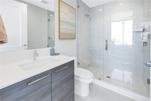 bathroom with tile patterned floors, vanity, an enclosed shower, and toilet