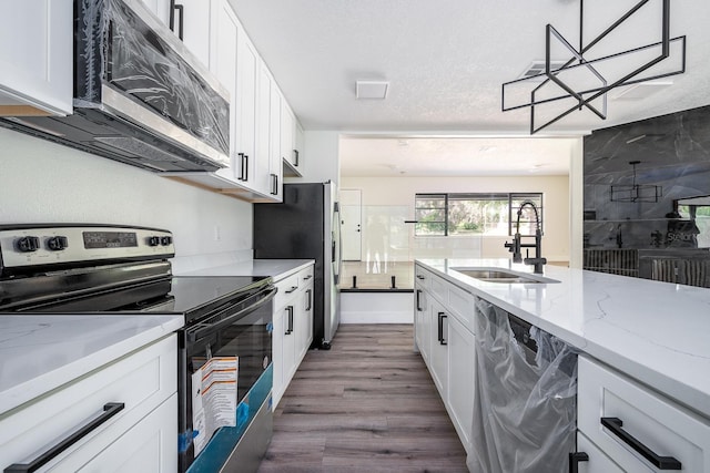 kitchen featuring sink, appliances with stainless steel finishes, hardwood / wood-style floors, light stone counters, and white cabinets