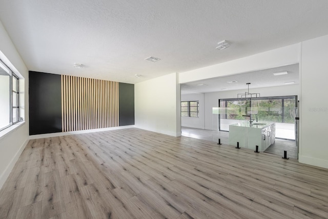 spare room featuring sink, light hardwood / wood-style floors, and a textured ceiling