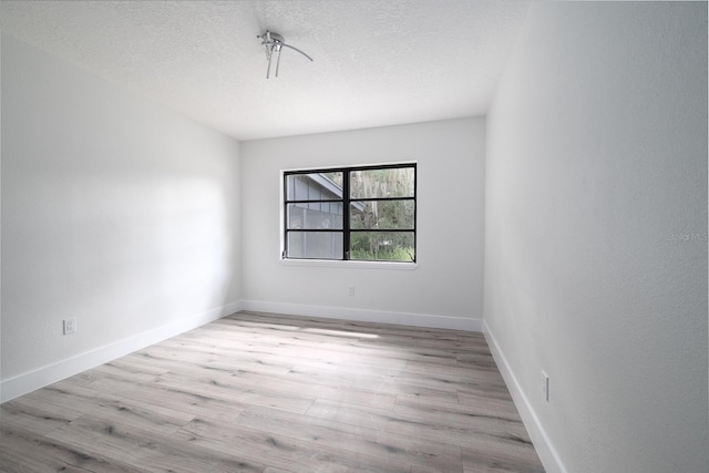 spare room with a textured ceiling and light hardwood / wood-style floors