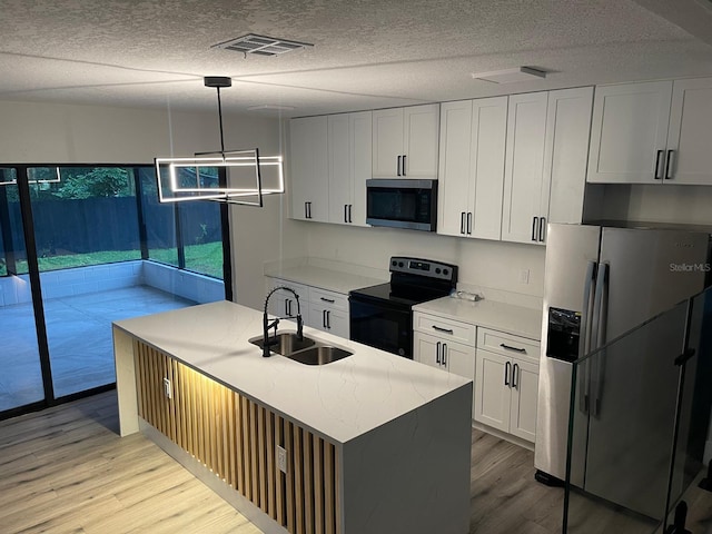 kitchen with sink, decorative light fixtures, appliances with stainless steel finishes, an island with sink, and white cabinets