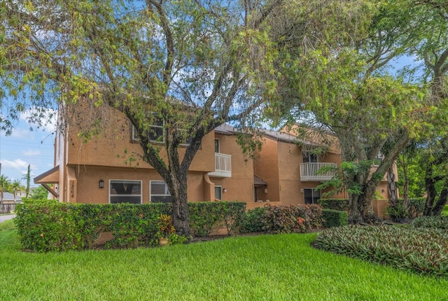 view of front of house with a balcony and a front lawn