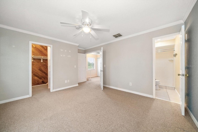 unfurnished bedroom with ceiling fan, ornamental molding, a walk in closet, and light carpet