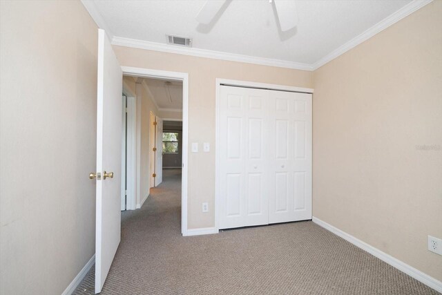 unfurnished bedroom featuring carpet, ceiling fan, a closet, and ornamental molding